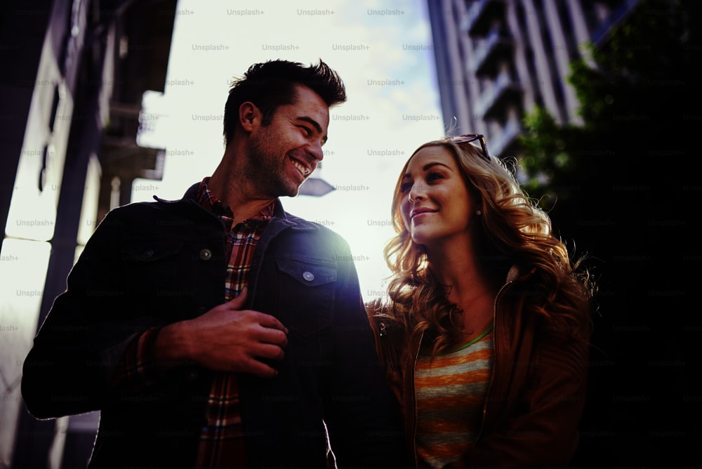romantic couple walking through downtown los angeles with lens flare