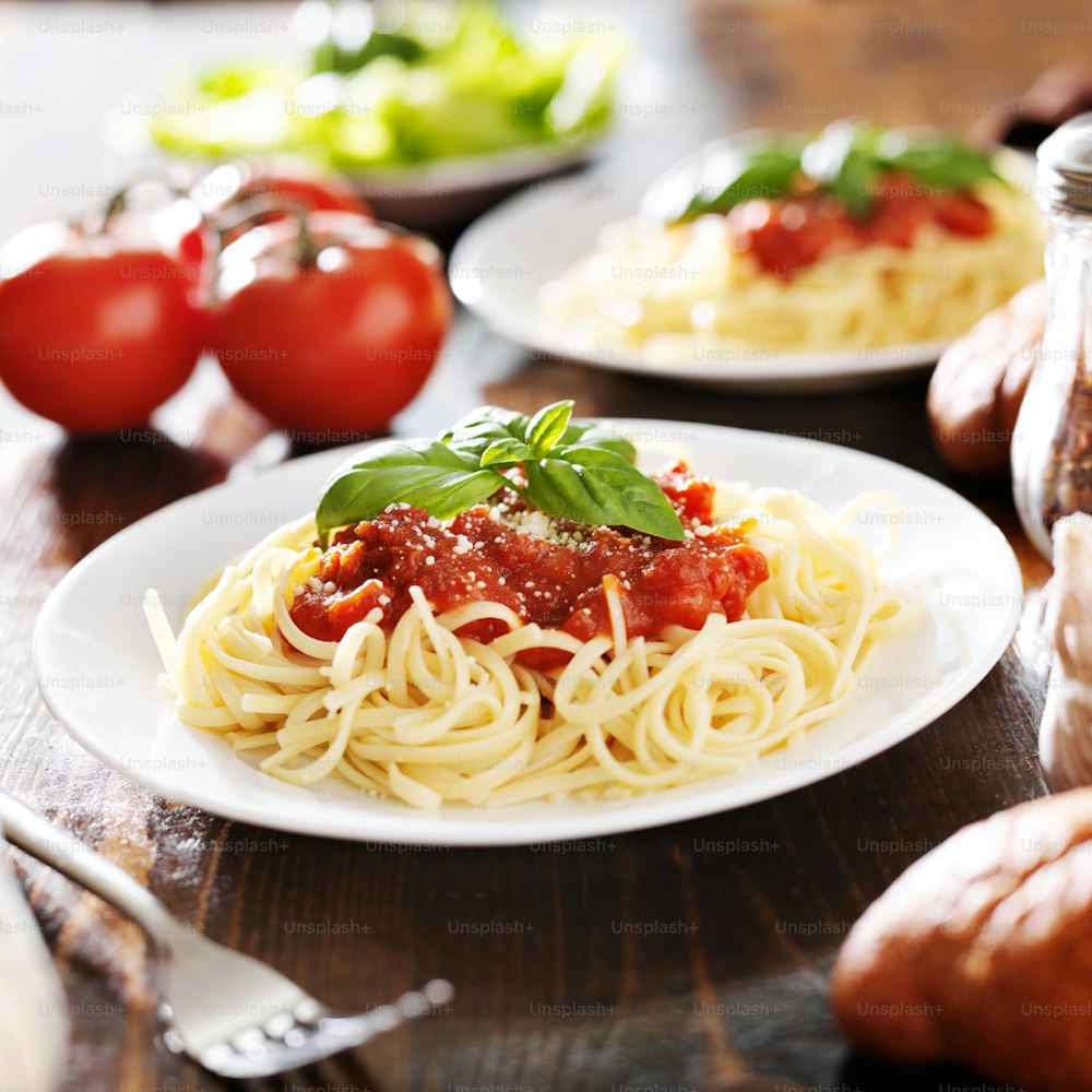 Dos platos de espaguetis con guarnición de albahaca tomados en primer plano con enfoque selectivo