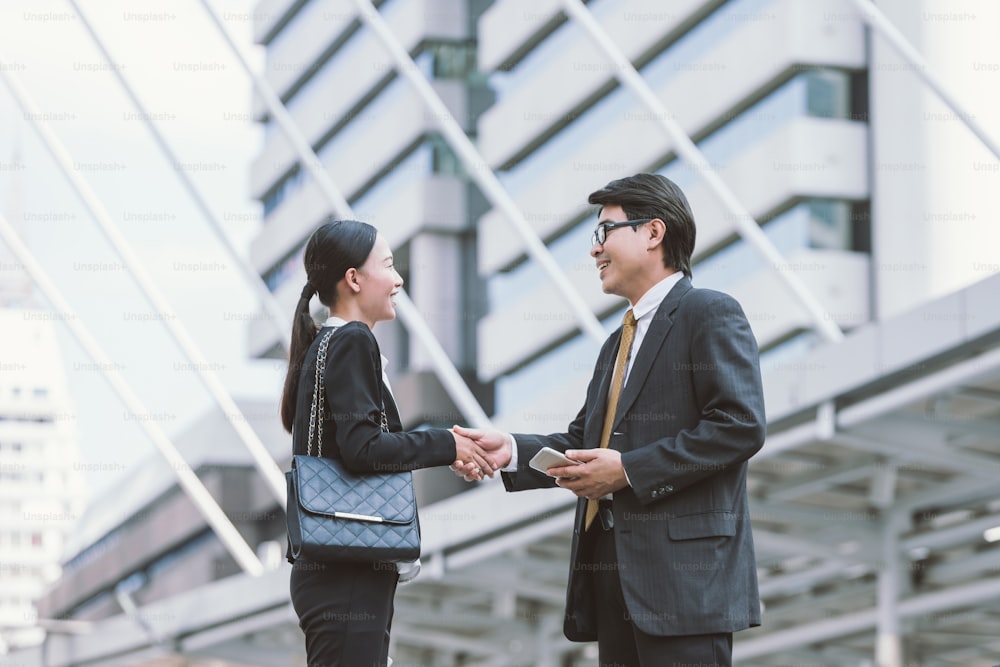 Moderne Geschäftsleute handeln.Partner schütteln sich die Hand und stehen vor seinem Büro. Hintergrund der Stadt. Handshake-Konzept