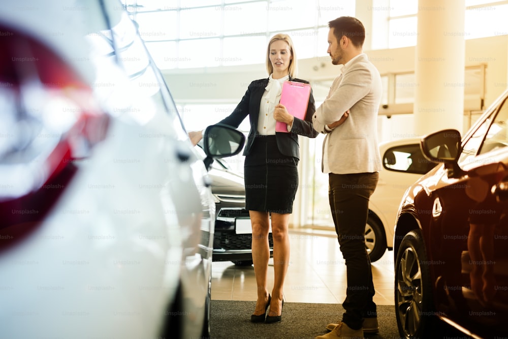 Car salesperson assisting customer at car dealership