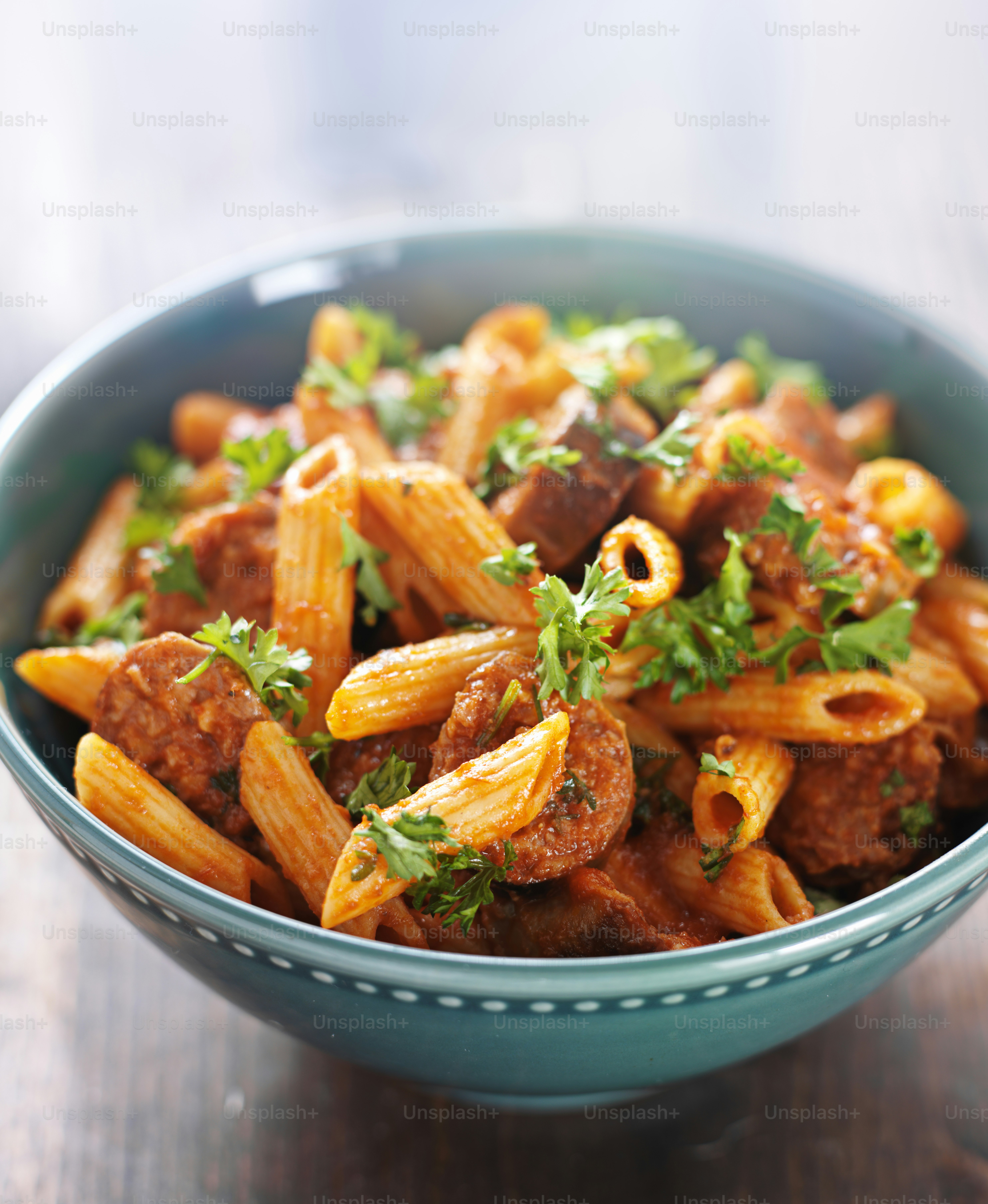 Foto de primer plano de un plato de pasta rigatoni con salchicha disparada con enfoque selectivo extremo.