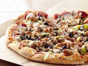 段ボール箱に鎮座するスプリームピザに、イタリアンソーセージ、ピーマン、ブラックオリーブ、マッシュルーム、ペパロニを添えて。