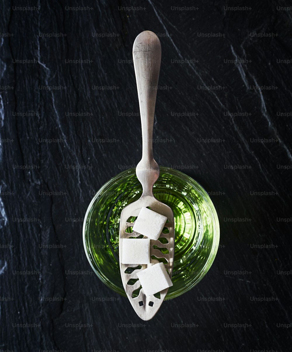 absinthe with sugar cubes and spoon flat lay composition on top of dark slate