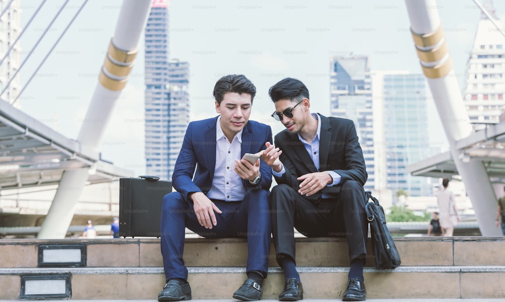 Jovens empresários asiáticos usam e brincam com seu smartphone.