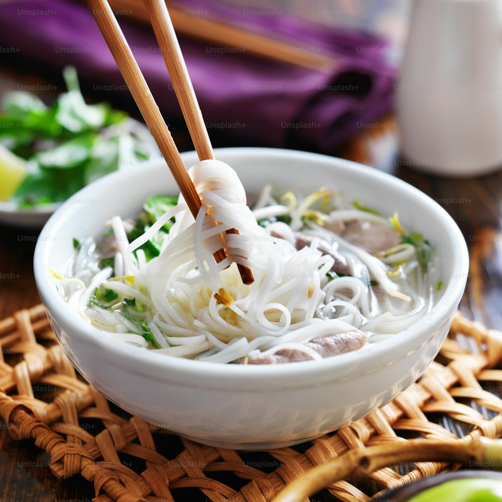 eating a bowl of pho with chopsticks close up photo