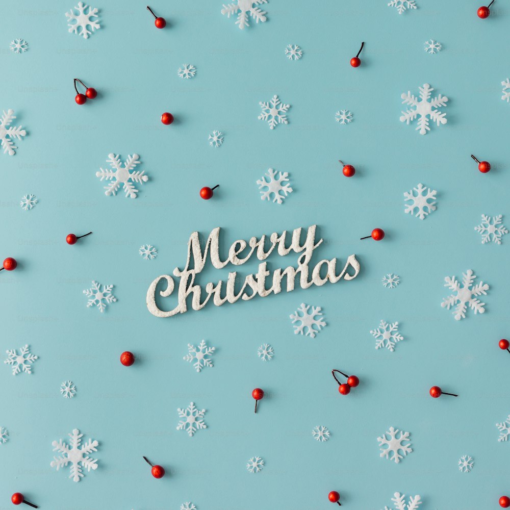 파란색 배경에 눈송이와 붉은 열매로 만든 크리스마스 패턴. 겨울 개념입니다. 플랫 레이.