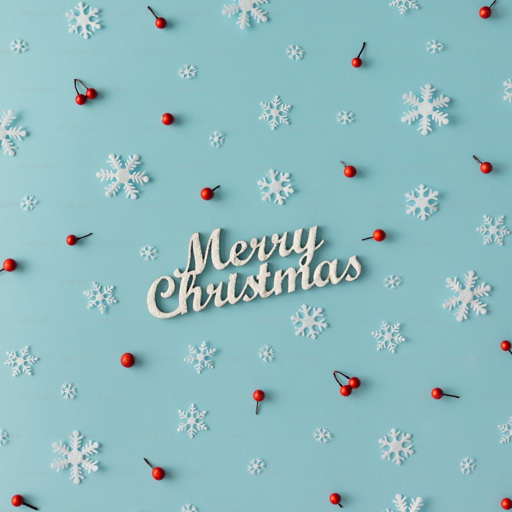 Christmas pattern made of snowflakes and red berries on blue background. Winter concept. Flat lay.