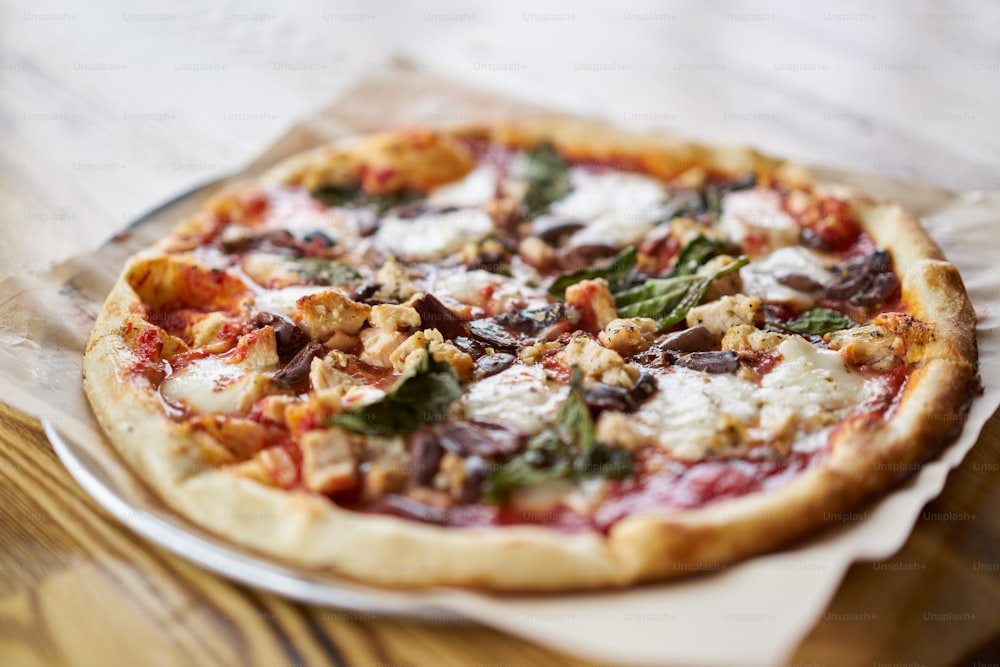 Auténtica pizza al horno de ladrillo con queso ovalina y pollo en la mesa de la pizzería