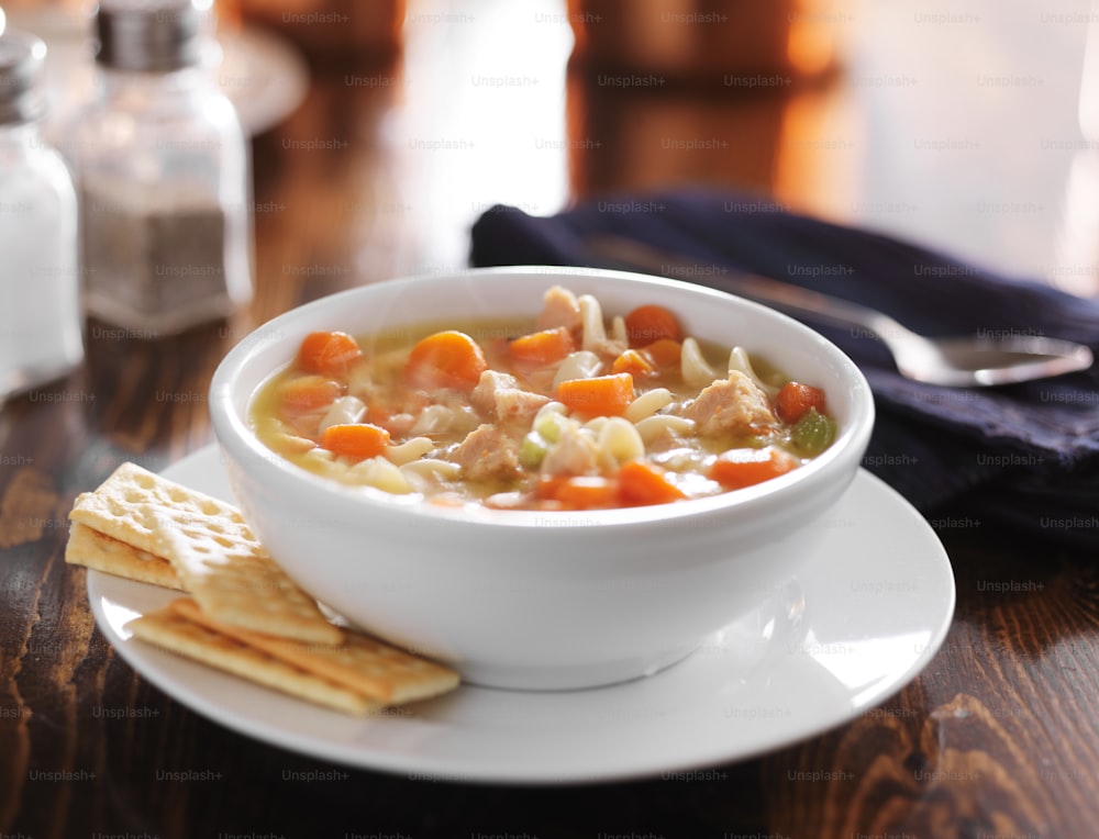 hot bowl of chicken noodle soup on wooden table