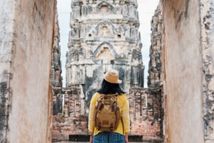 Asian tourist woman take a photo of ancient of pagoda temple thai architecture at Sukhothai,Thailand. Female traveler in casual thai cloths style visiting city concept