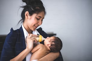Businesswoman working from home, holding baby girl