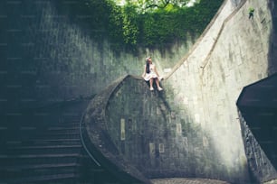 シンガポール、フォート・カニング・パークのトンネル内にある地下踏切の螺旋階段の円形階段に座る少女旅行者