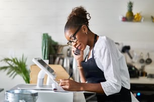 friendly waitress taking order on phone at restaurant and writing on notepad during the day