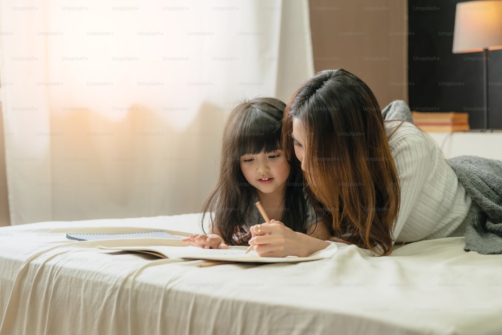 Schöne asiatische alleinerziehende Mutter mit süßer Tochter Glück Moment Zeit Hausaufgaben unterrichten HomeSchool Ideen Konzept Haus Hintergrund