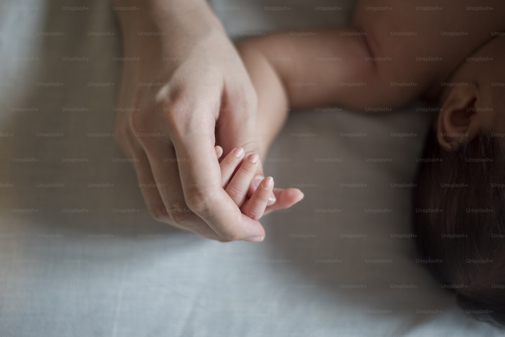 Gros plan d’une main de nouveau-né dans la main de sa mère pendant son sommeil
