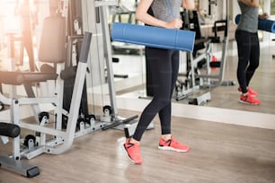 La mujer deportiva joven bonita es el entrenamiento con la colchoneta en el gimnasio, estilo de vida saludable