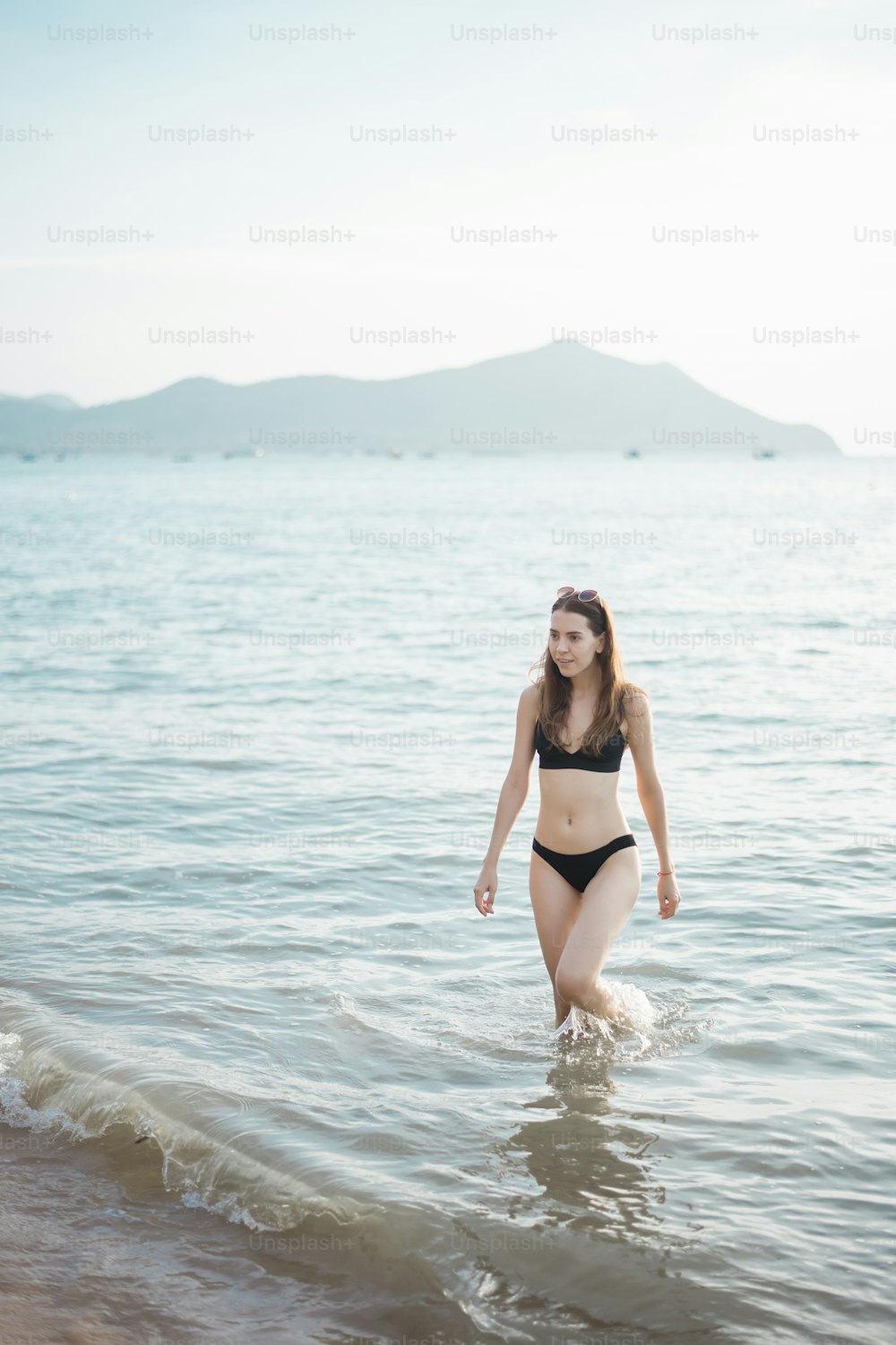 Schöne Frau im schwarzen Bikini geht vom Meer aus, Sommerkonzept