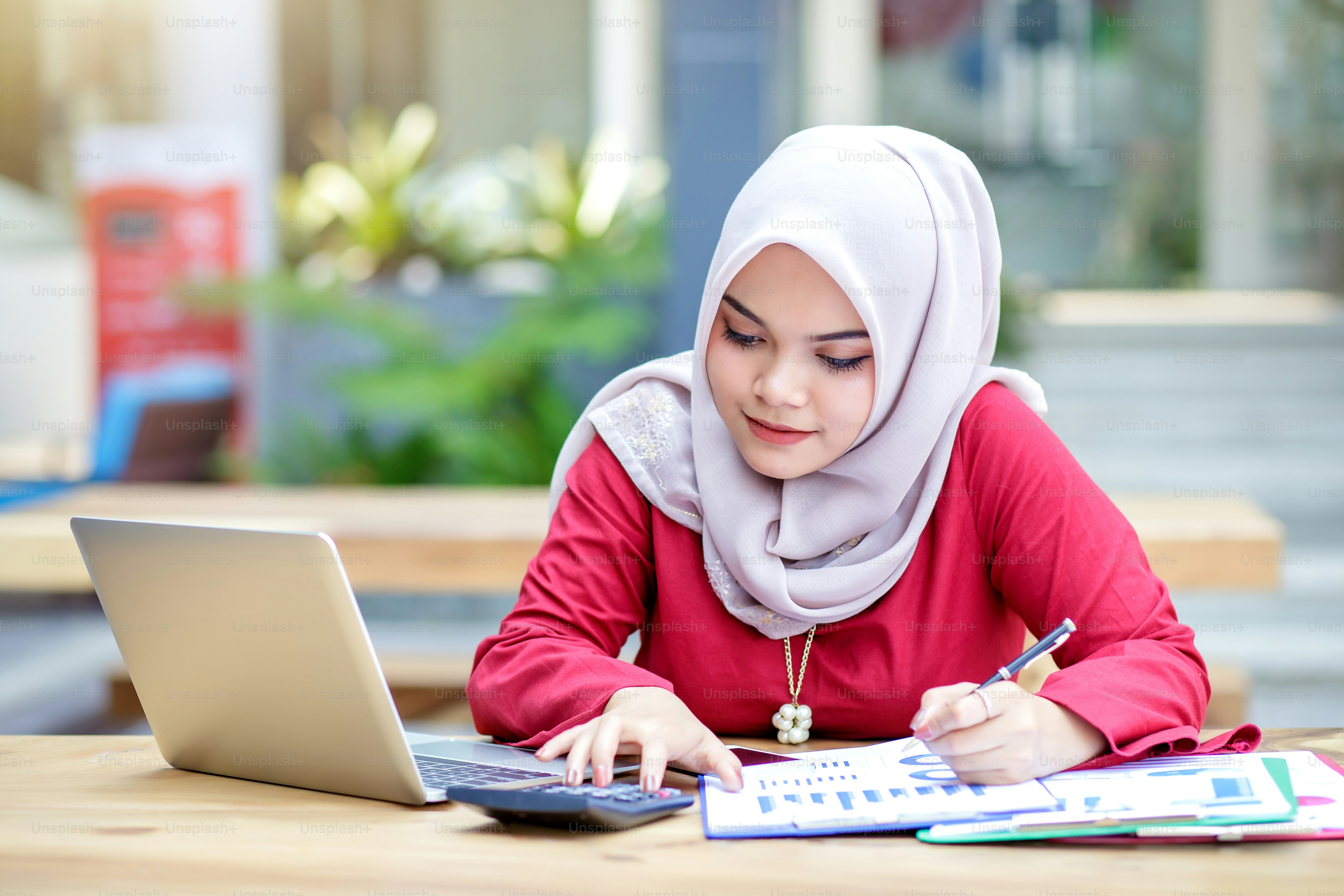 Young asian muslim woman working on laptop outdoor.