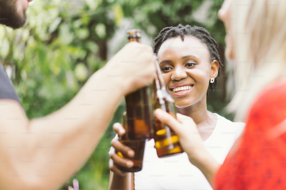 Amigos conversando y brindando cervezas al aire libre. La gente de la fiesta bebe, brinda, celebra.