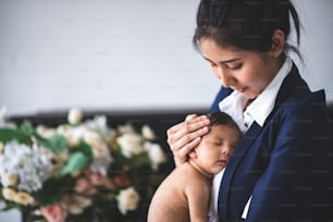 Businesswoman working from home, holding baby girl