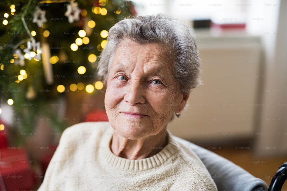 A portrait of a lonely senior woman in wheelchair at home at Christmas time.