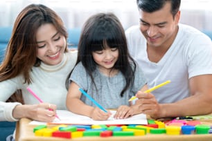 happiness lovely father mother teach homework for little preety daughter in living room family concept