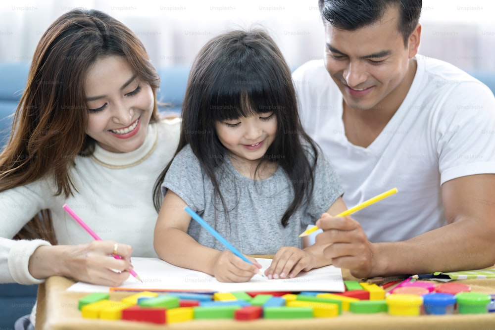 happiness lovely father mother teach homework for little preety daughter in living room family concept