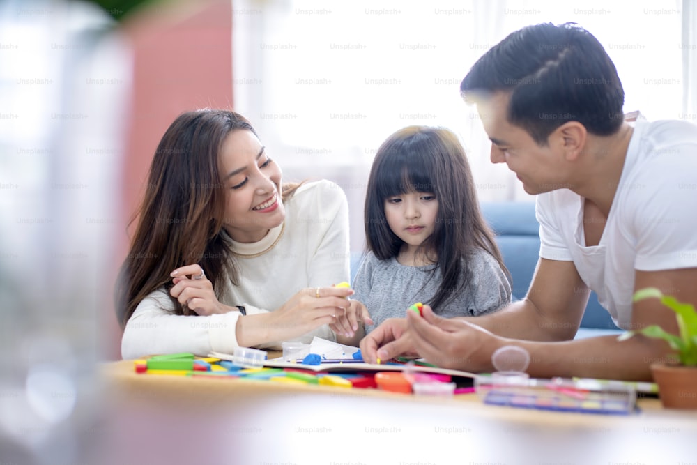 happiness lovely father mother teach homework for little preety daughter in living room family concept