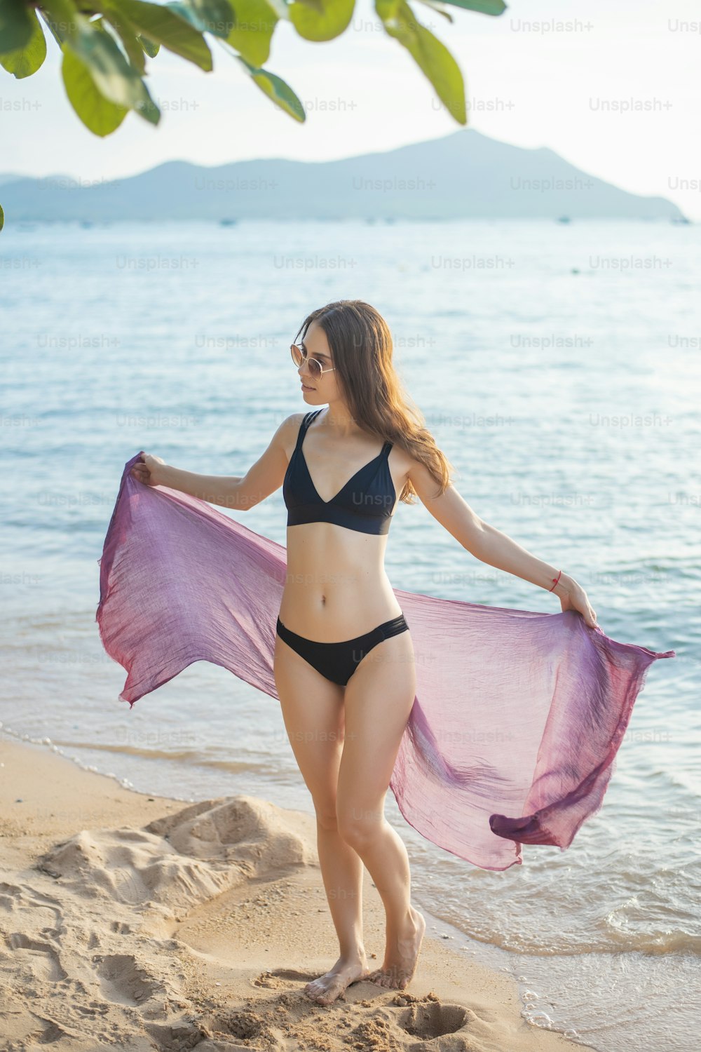 Schöne Frau im schwarzen Bikini entspannt am Strand, Sommerkonzept