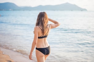 검은 비키니를 입은 아름다운 여자가 해변에서 휴식을 취하고 있다, 여름 컨셉