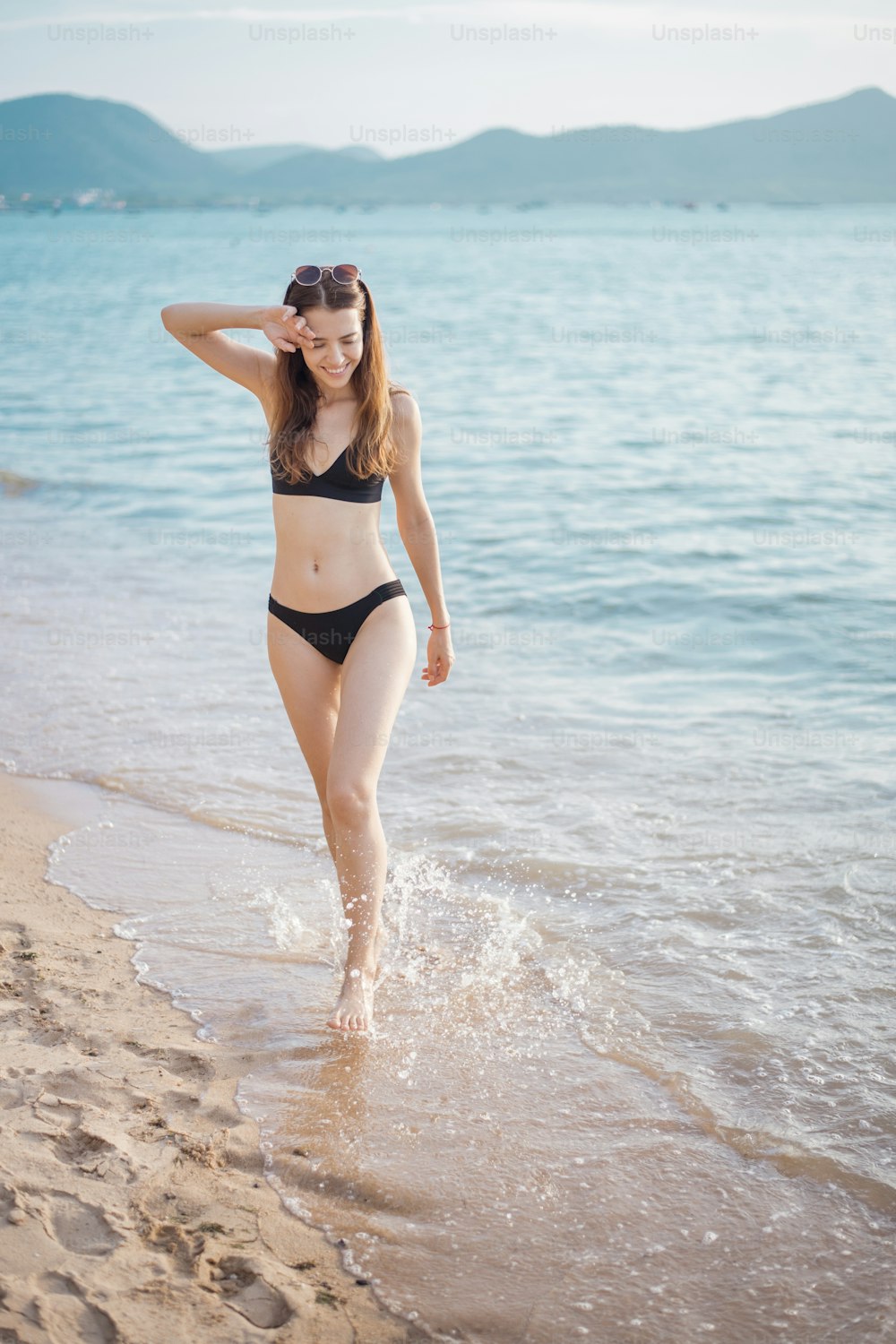 Belle femme en bikini noir marche de la mer, concept d’été