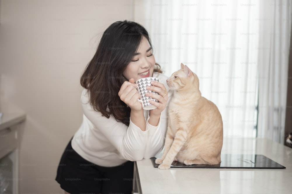 Hermosa mujer asiática amante de los gatos está jugando con el gato en su habitación
