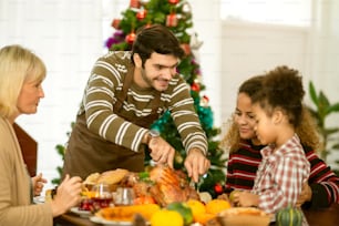 ダイニングルームで感謝祭のランチを食べながらコミュニケーションをとる幸せなアメリカの家族のお祝いのアイデアのコンセプト