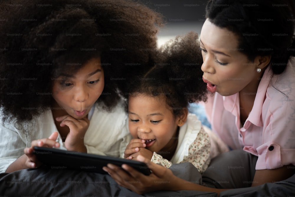 Mother and child are enjoying watching movies on tablet, African people