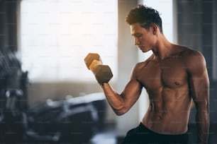 Handsome man with dumbbells in functional training fitness gym