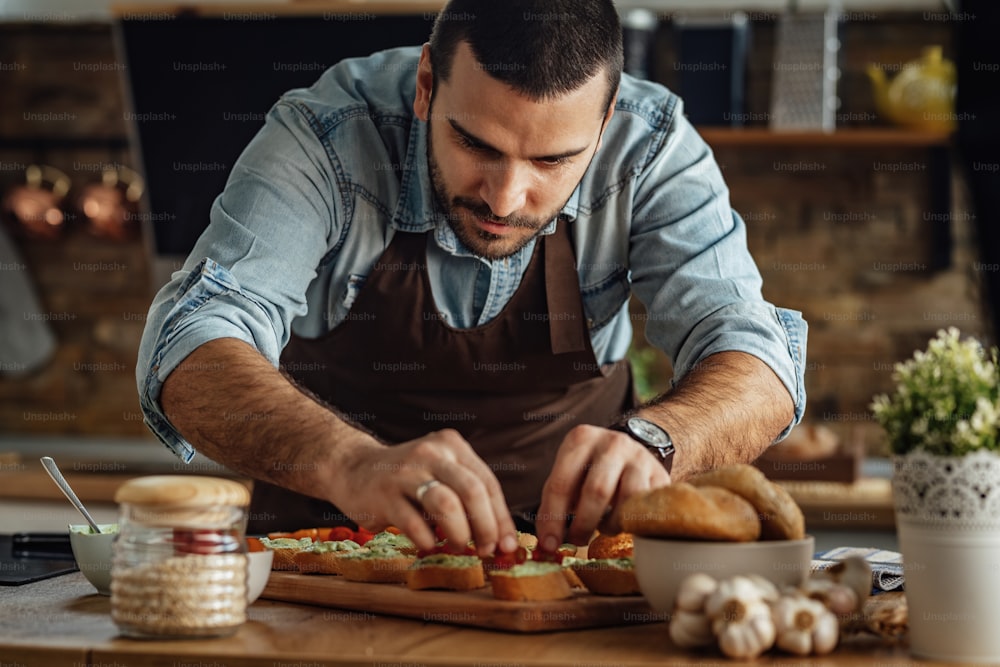 Young man preparing healthy food and making bruschetta in the kitchen.
