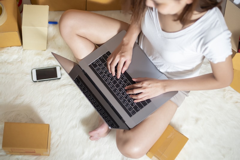 Woman entrepreneur owner SME business is checking order with smartphone, laptop and packaging box to send her customer