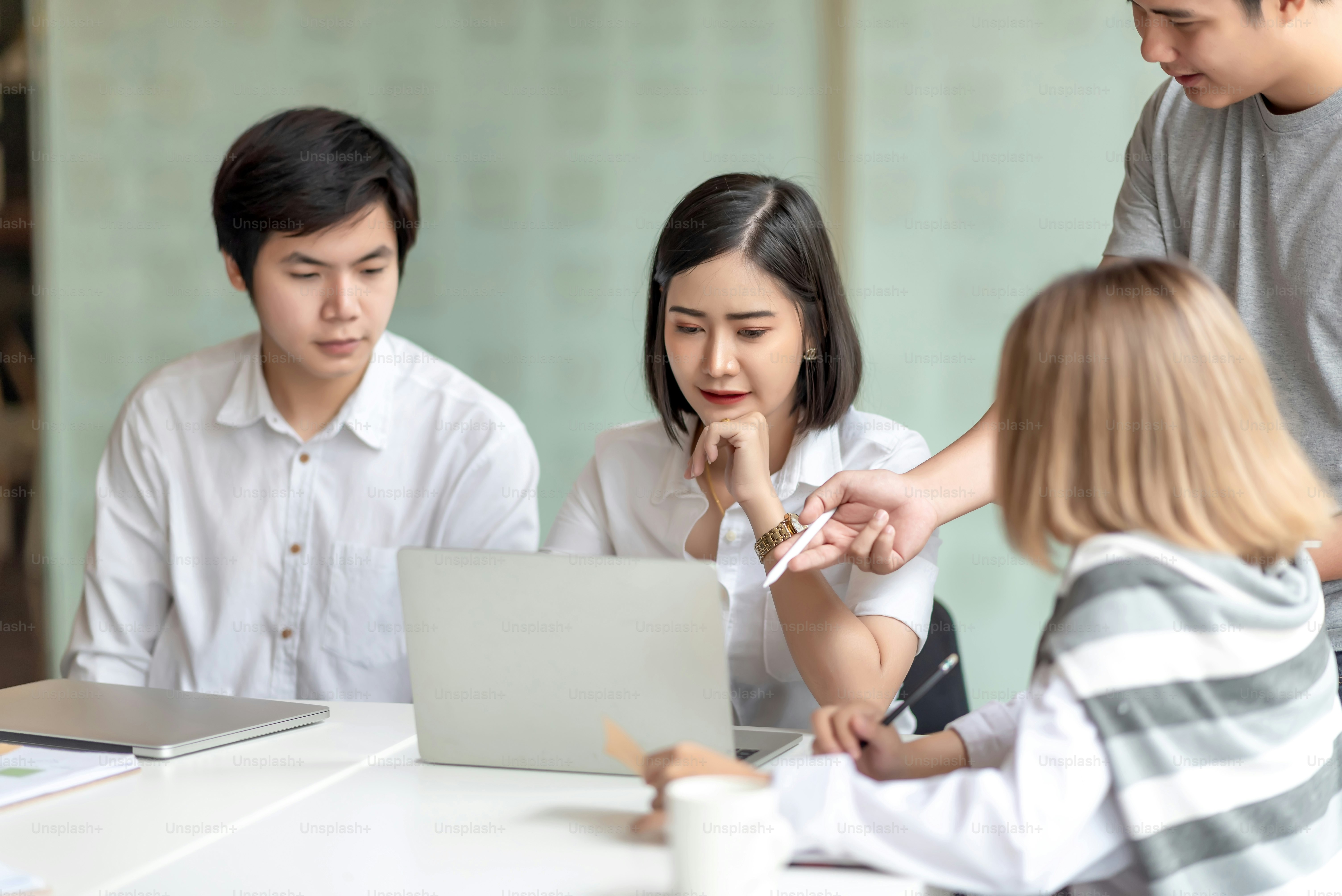 Gruppo di giovani uomini d'affari asiatici che lavorano e fanno brainstorming e scambiano idee durante l'incontro.