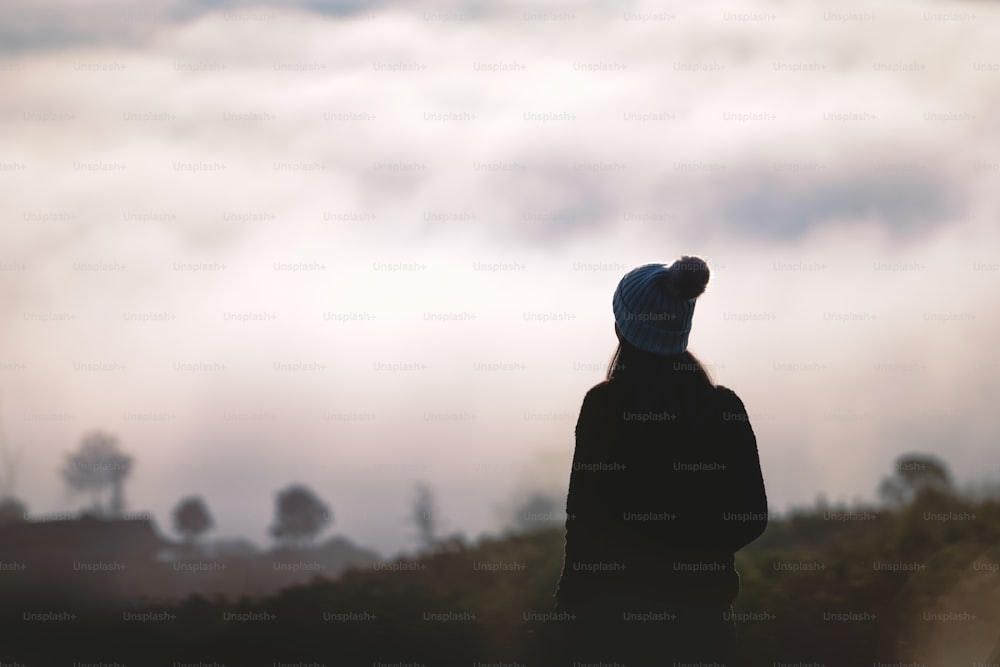 Silhouette adult woman solo traveller. She has standing relax breath among nature of sunrise in the morning with cloud. Trendy destination travel on winter at Chiang mai, Thailand.