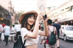 Junge asiatische süße Brille Mädchen Hipster Stil Reisende. Rucksack solo lokale Reisen machen ein Foto mit Kamera. Sightseeing auf dem Straßenmarkt der Khaosan Road und dem Wahrzeichen von Lebensmitteln. Bangkok, Thailand.