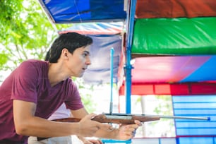 Young couple playing shooting games at an amusement park, theme park, having fun