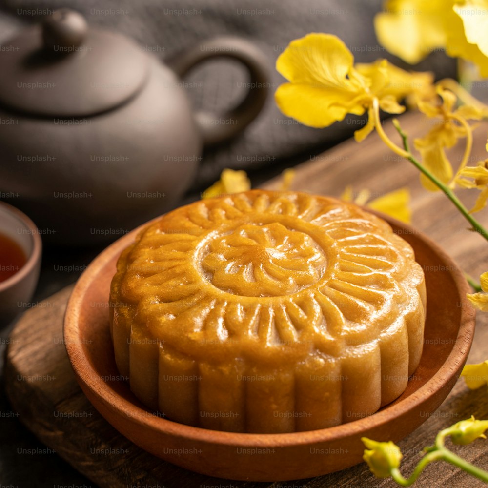 Mooncake, Moon cake for Mid-Autumn Festival, concept of traditional festive food on black slate table with tea and yellow flower, close up, copy space.