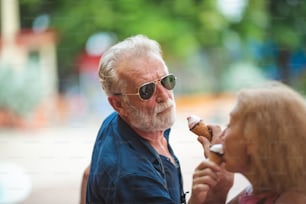 Senior couple relaxing at an amusement theme park, eating and enjoy with Ice cream on summer in concept of happy