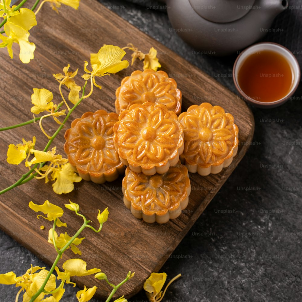 Mooncake, bolo da Lua para o Festival do Meio do Outono, conceito de comida festiva tradicional na mesa de ardósia preta com chá e flor amarela, close-up, espaço de cópia.