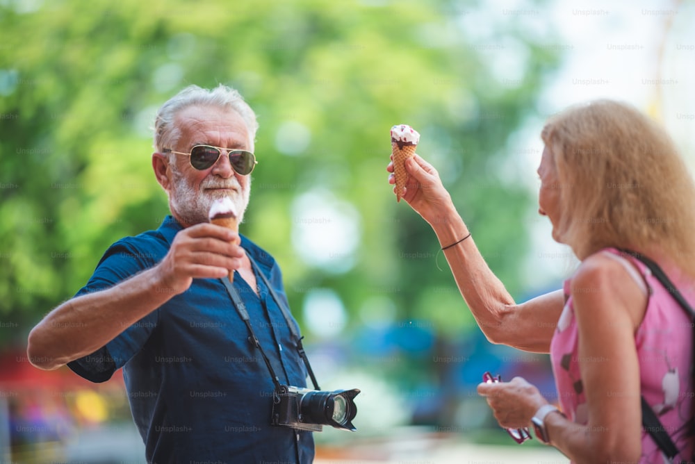 Casal de idosos relaxando em um parque temático de diversões, comendo e desfrutando com sorvete no verão no conceito de feliz