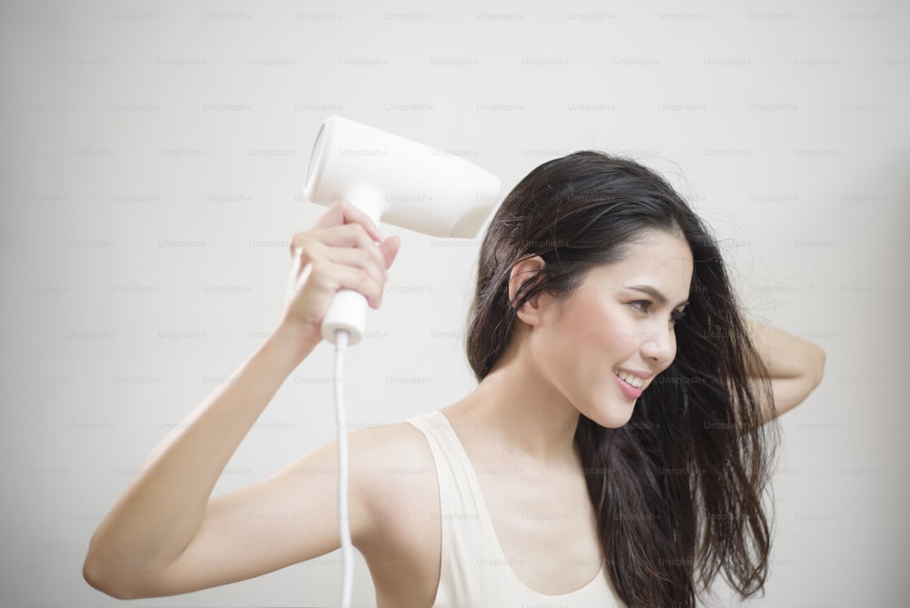 A woman is drying her hair after showering