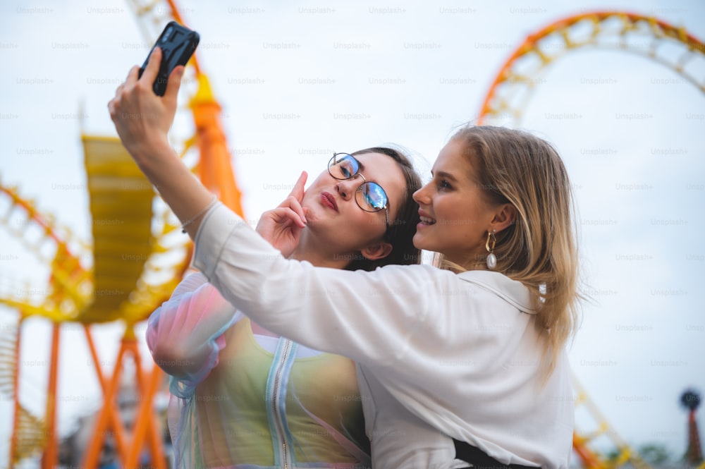 Chica alegre y sonriente haciendo selfie, retrato al aire libre divirtiéndose en el parque temático de atracciones.