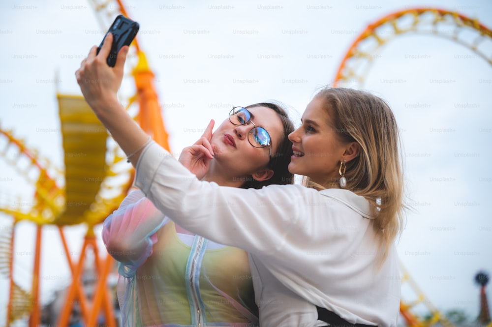 Ragazza sorridente gioiosa che fa selfie, ritratto all'aperto che si diverte nel parco a tema di divertimenti.