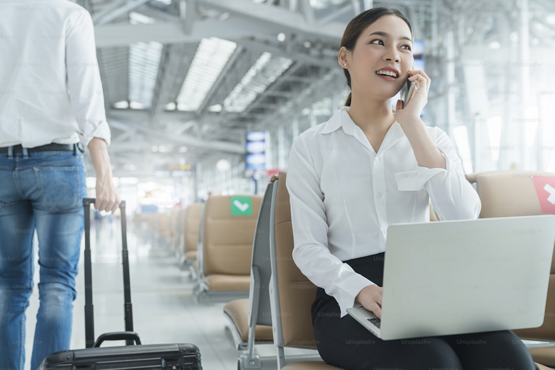 Social distancing, businesswoman sit working with laptop and smartphone keeping distance away from each other to avoid c