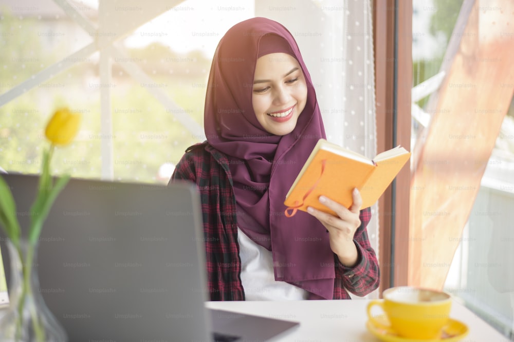 Muslim woman with hijab is working with laptop computer in coffee shop